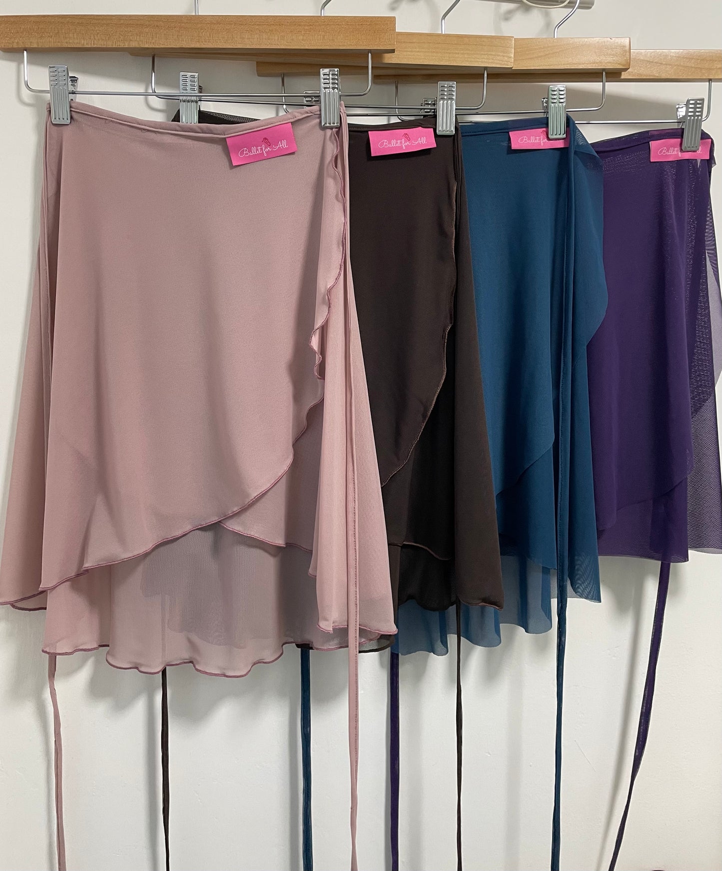 Four skirts in different colors hanging on a rack with pink tags.